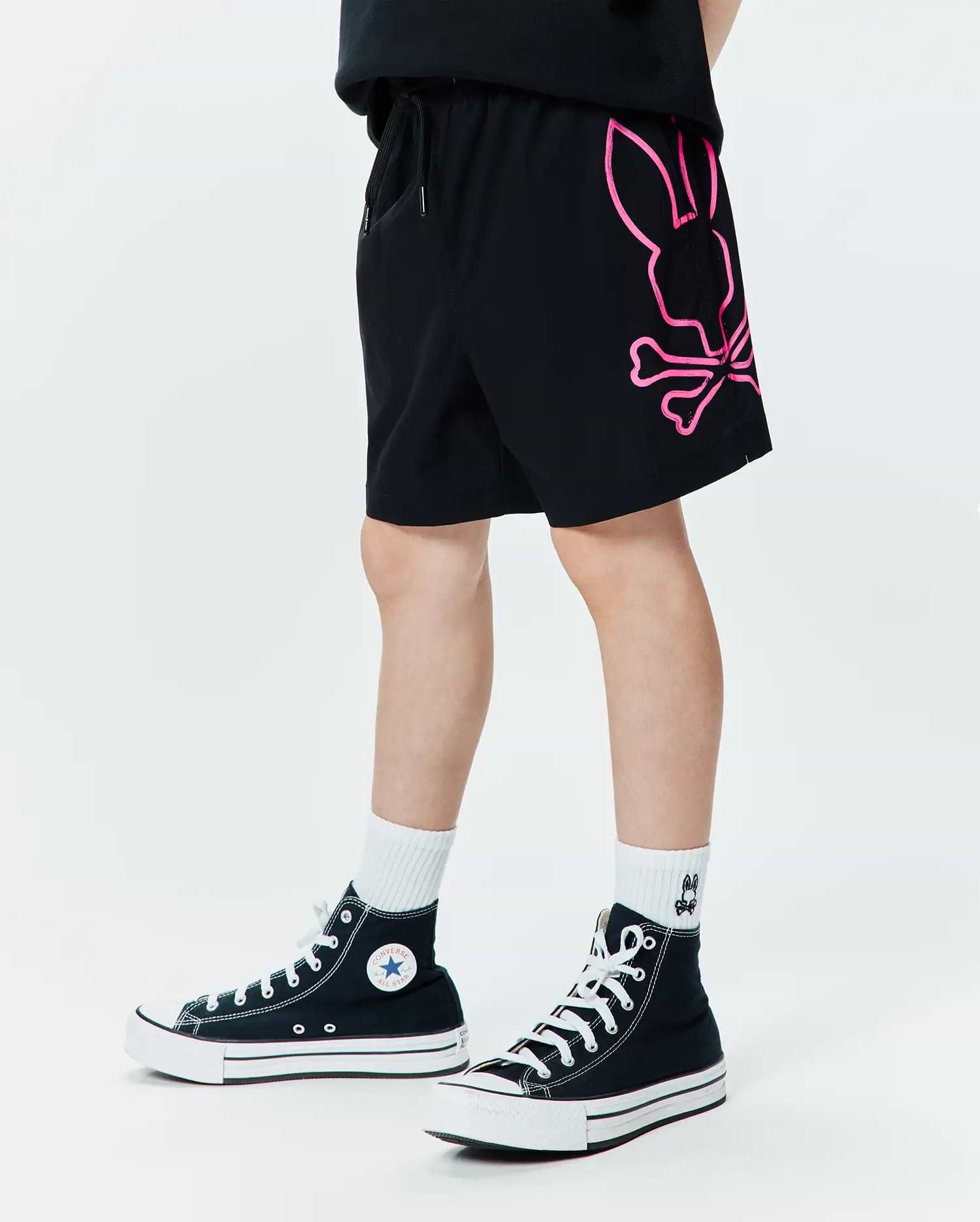 Kids Duncan Bunny Print Swim Trunk in black, featuring a large neon pink graphic Psycho Bunny skull logo on the left leg, with a relaxed fit and smooth swim fabric.