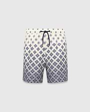 Kids Tobias Swim Trunk in cream with a navy blue diamond grid pattern featuring repeated Psycho Bunny skull logos, a relaxed fit, and a navy drawstring. The pattern intensifies towards the hem.