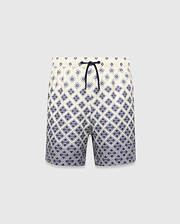Kids Tobias Swim Trunk in cream with a navy blue diamond grid pattern featuring repeated Psycho Bunny skull logos, a relaxed fit, and a navy drawstring. The pattern intensifies towards the hem.
