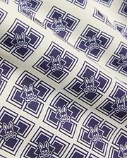 Kids Tobias Swim Trunk in cream with an all-over navy blue geometric square pattern featuring repeated Psycho Bunny skull logos on smooth woven fabric.