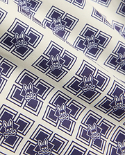 Kids Tobias Swim Trunk in cream with an all-over navy blue geometric square pattern featuring repeated Psycho Bunny skull logos on smooth woven fabric.