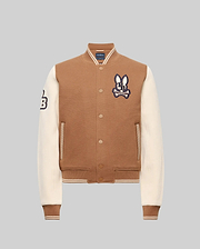 The Psycho Bunny KIDS WADE KNIT BOMBER (KO1100001) is a brown varsity jacket with cream sleeves, ribbed cuffs and hem, bunny patch on the chest, "B" patch on the sleeve, front pockets, and snap button closures. Made from a premium cotton blend.