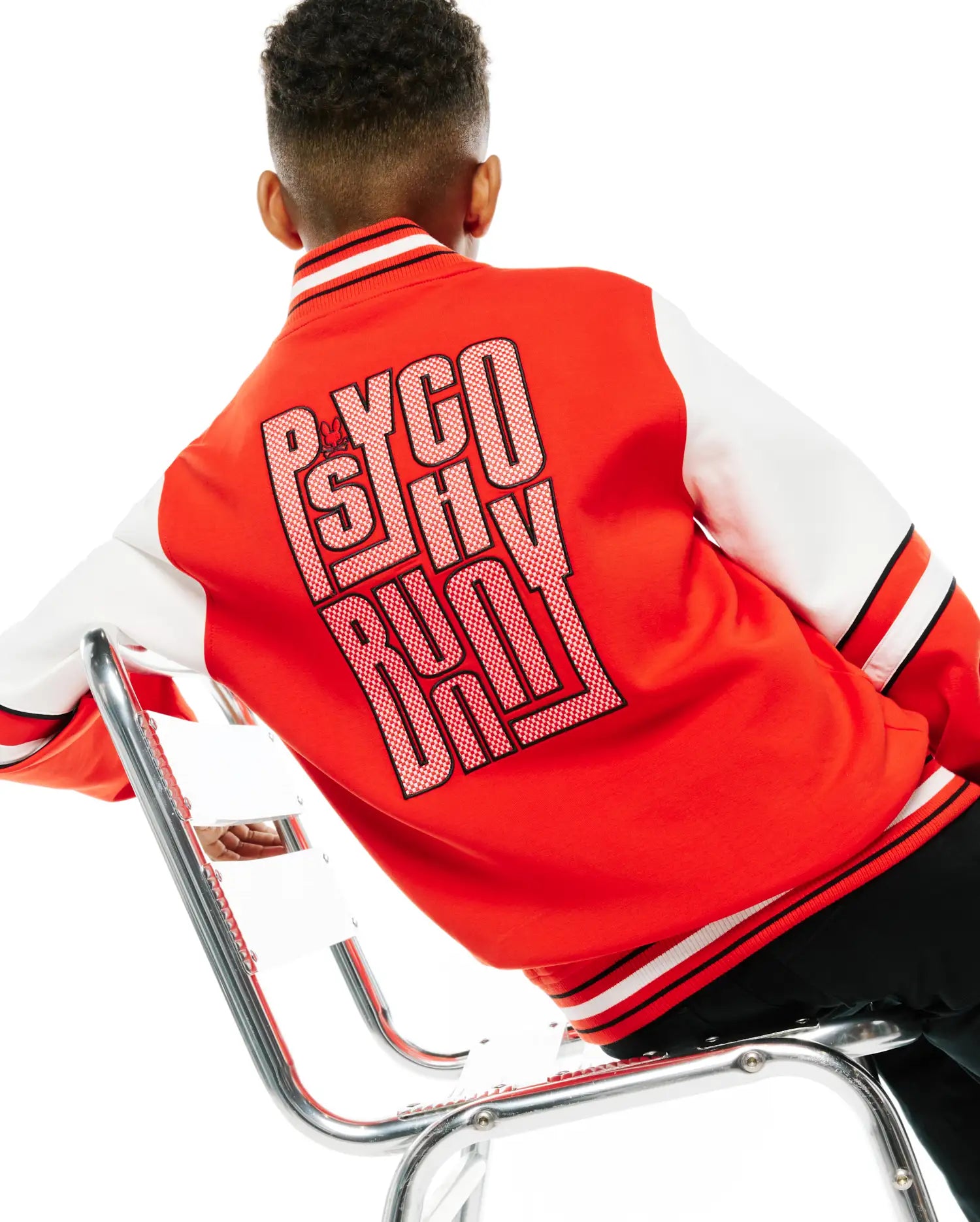Kids Joey Knit Bomber in red with white sleeves, featuring a large Psycho Bunny text graphic on the back with a small bunny skull, and black and white striped ribbed trim.