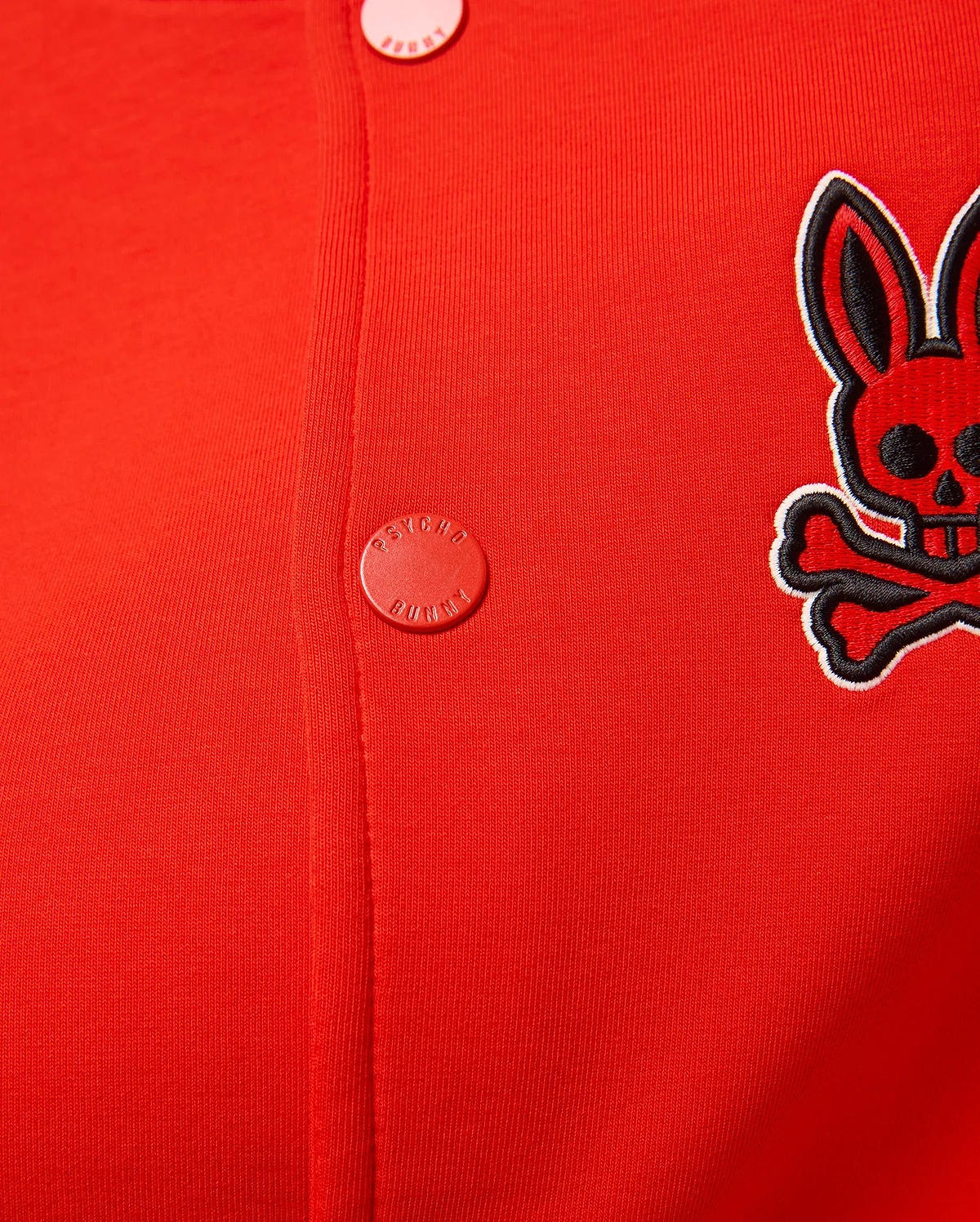 Kids Joey Knit Bomber in vibrant red, featuring a fine ribbed knit texture, an embroidered black and white Psycho Bunny skull logo on the left chest, and red branded snap buttons.