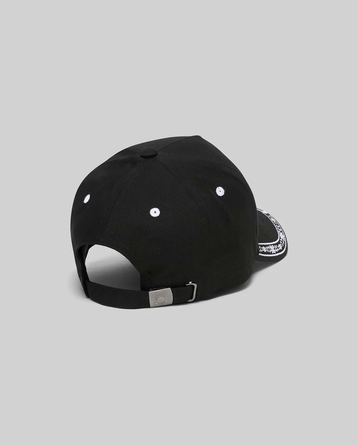 Black Kids Luke Trucker Cap featuring white embroidered eyelets, a white bandana-style pattern on the side brim, and a small engraved Psycho Bunny skull logo on the metal adjustable back clasp.