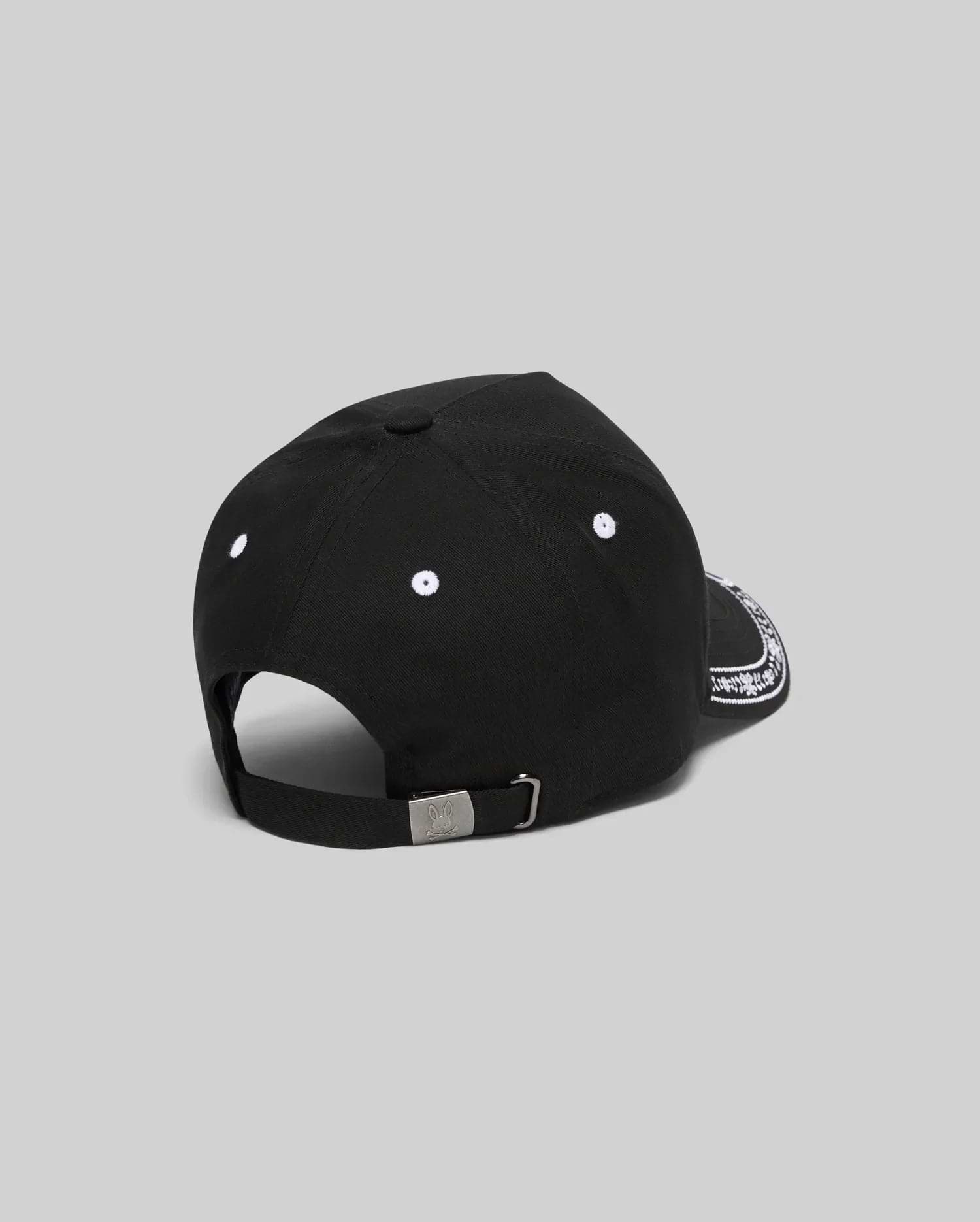Black Kids Luke Trucker Cap featuring white embroidered eyelets, a white bandana-style pattern on the side brim, and a small engraved Psycho Bunny skull logo on the metal adjustable back clasp.