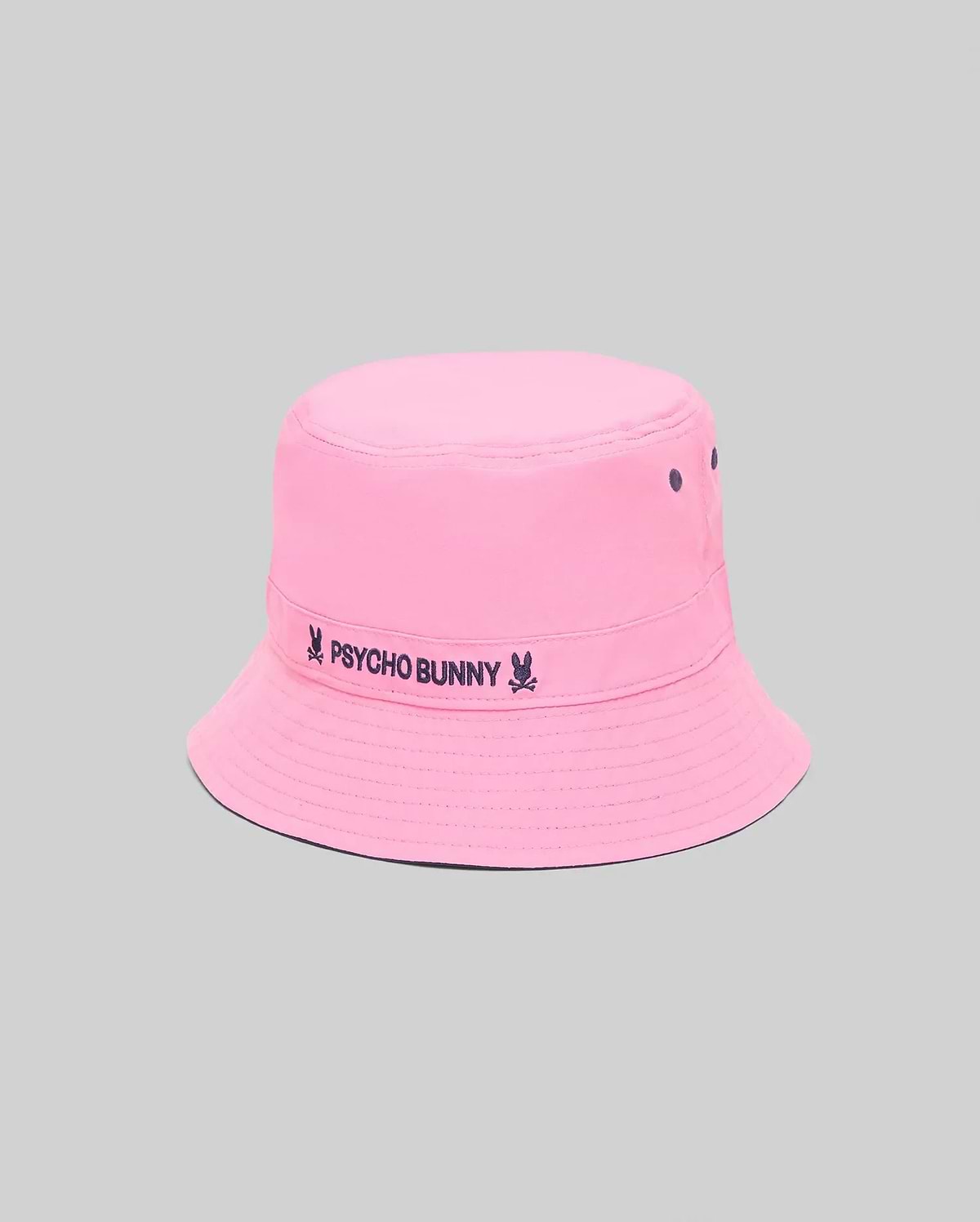 Kids Luke Reversible Bucket Hat in bright pink with dark blue embroidered Psycho Bunny text and skull logo on the band, featuring ventilation eyelets and a reversible design.