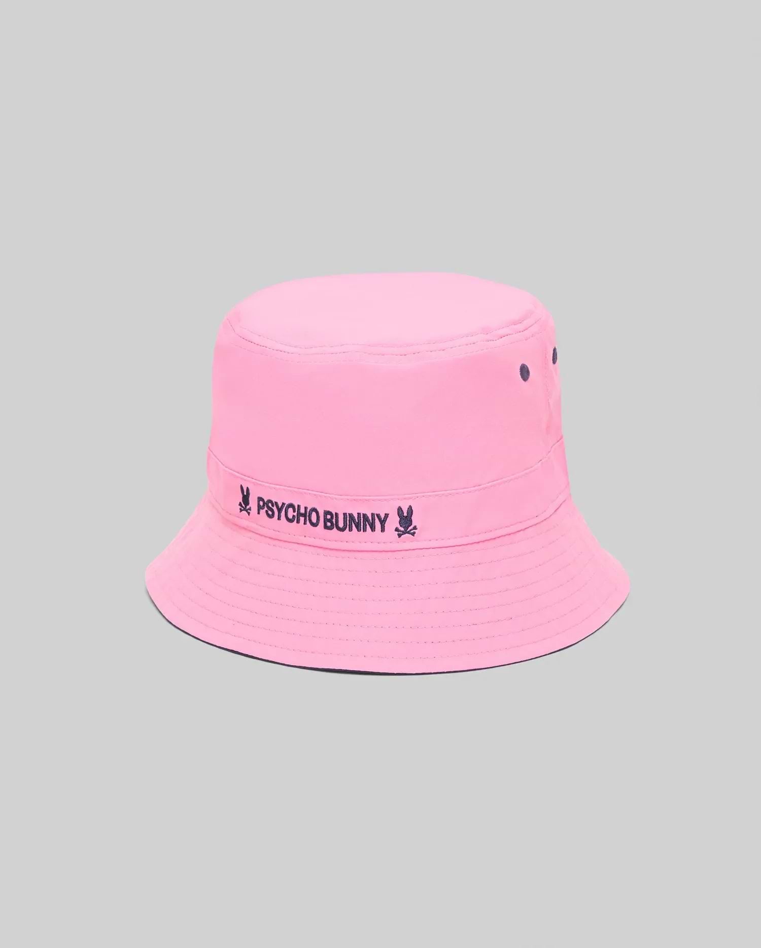 Kids Luke Reversible Bucket Hat in bright pink with dark blue embroidered Psycho Bunny text and skull logo on the band, featuring ventilation eyelets and a reversible design.
