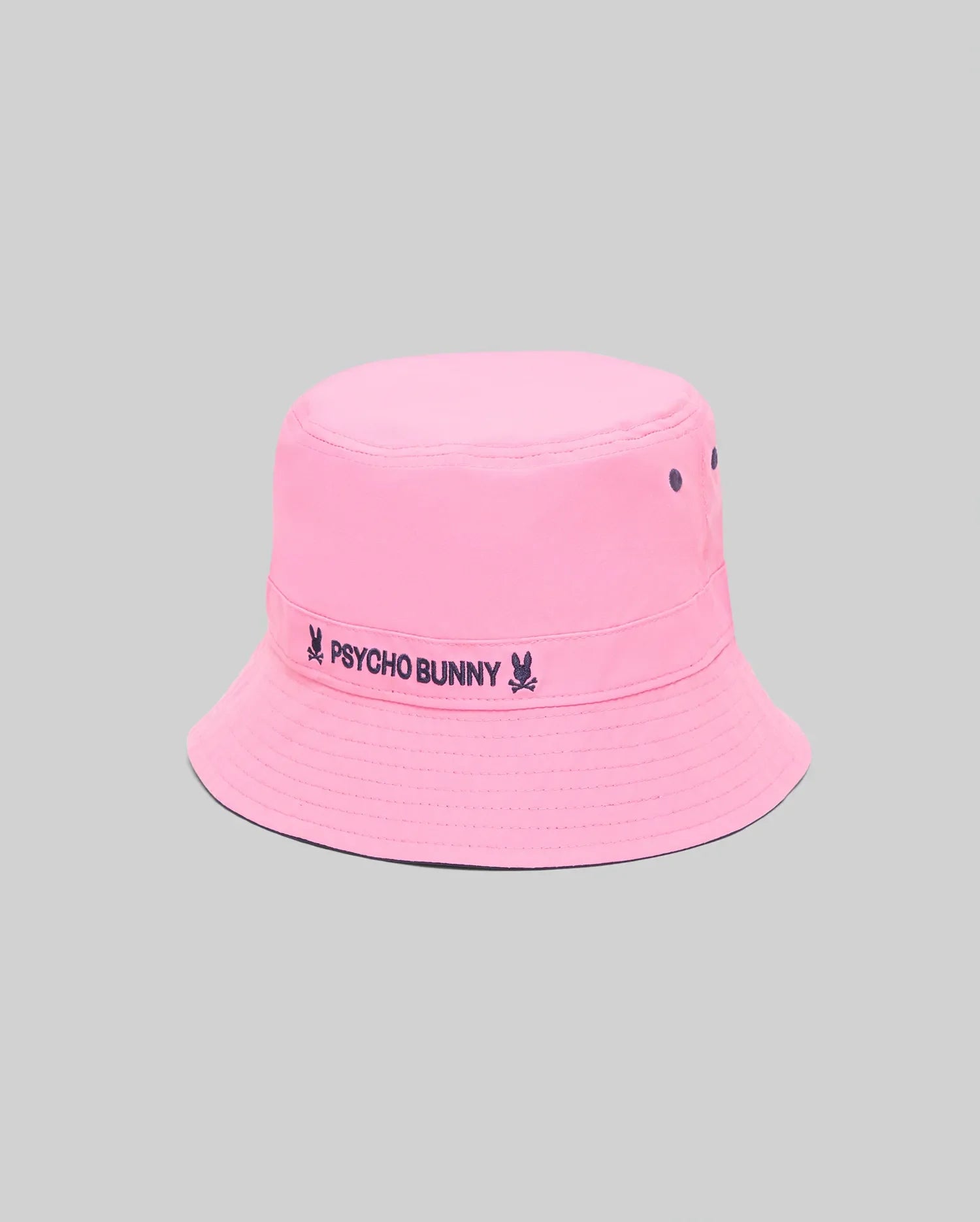 Kids Luke Reversible Bucket Hat in bright pink with dark blue embroidered Psycho Bunny text and skull logo on the band, featuring ventilation eyelets and a reversible design.