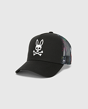 Kids Quintin Trucker Cap in black twill with a large white Psycho Bunny skull logo on the front. Features multicolor patterned mesh side and back panels with subtle bunny graphics.