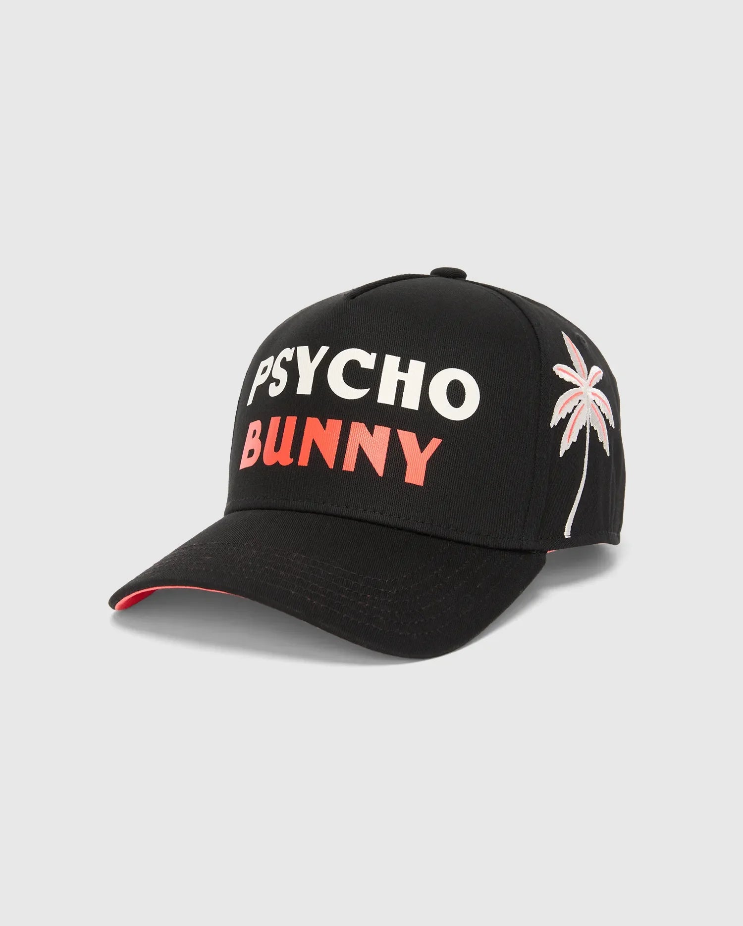 Black Kids Brad Trucker Cap with bold white PSYCHO and coral BUNNY text on the front, featuring an embroidered white and coral palm tree graphic on the right side, and a coral underside brim.