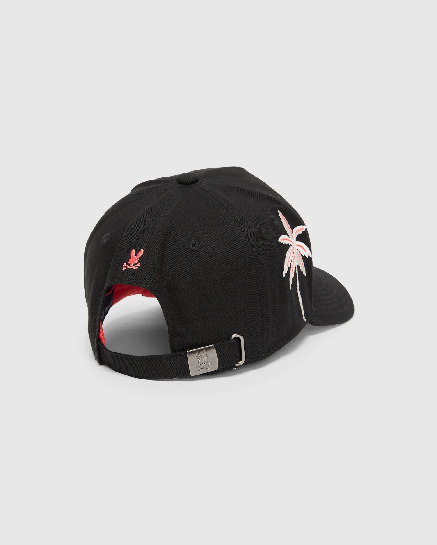 Black Kids Brad Trucker Cap with a red under brim, featuring a pink and white embroidered palm tree, a small red embroidered bunny skull on the back, and a metal buckle with an engraved bunny skull.