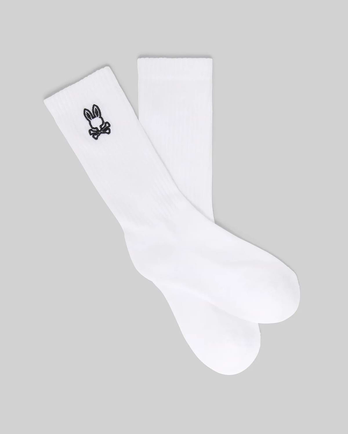 The Psycho Bunny KIDS 3 PACK SPORT SOCK (KO2200001) includes white crew socks made with soft Pima cotton and spandex, each featuring a small black bunny skull and crossbones logo near the top. Displayed on a gray background.