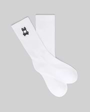 The Psycho Bunny KIDS 3 PACK SPORT SOCK (KO2200001) includes white crew socks made with soft Pima cotton and spandex, each featuring a small black bunny skull and crossbones logo near the top. Displayed on a gray background.