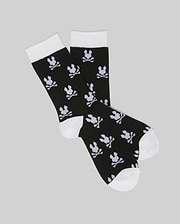 The Psycho Bunny KIDS 2 PACK ALL OVER BUNNY DRESS SOCK (KO2200003) features black socks with white toes, heels, and cuffs. A bunny skull-and-crossbones pattern is knit into soft stretch Pima cotton blend, shown on a light gray background.