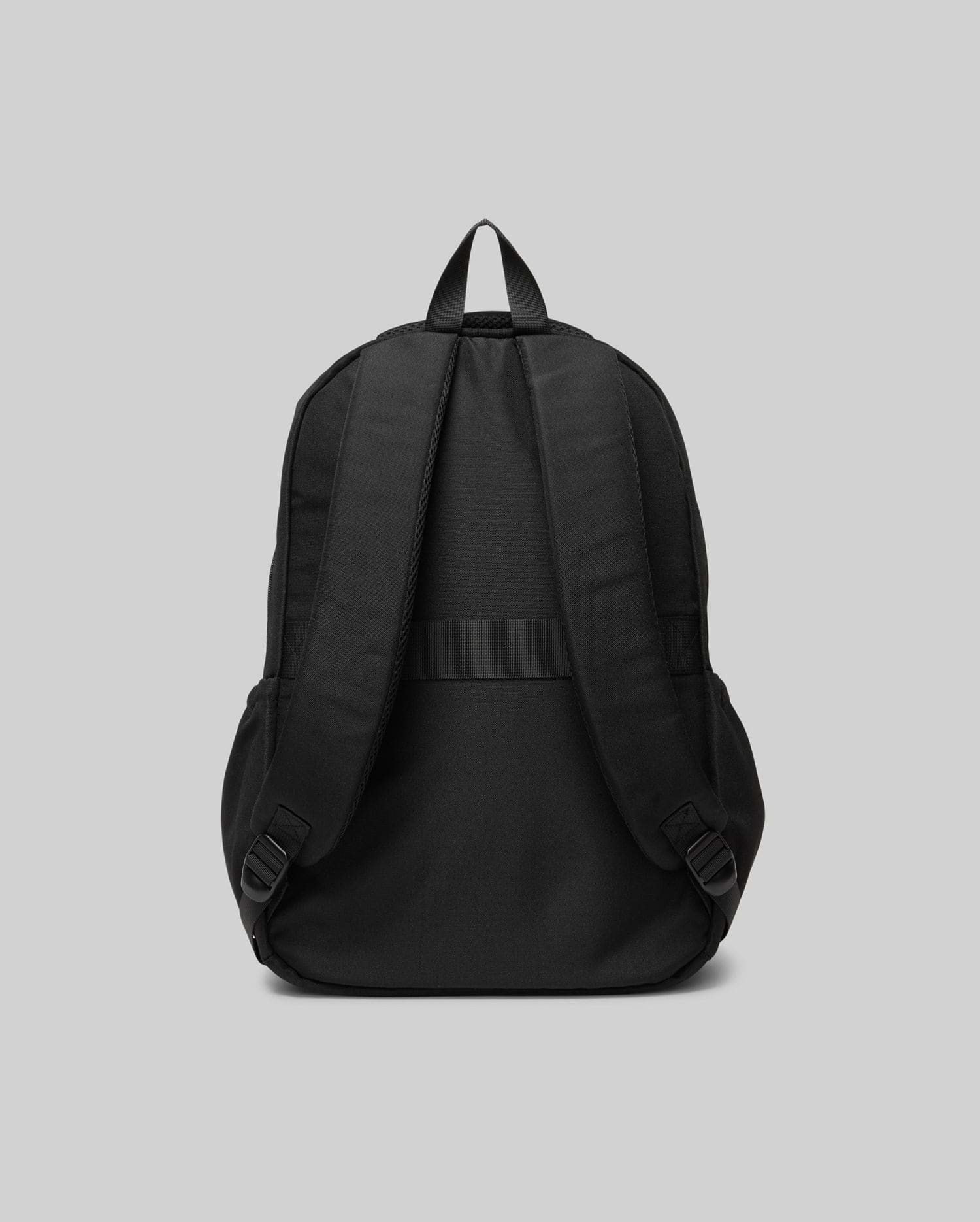The Psycho Bunny KIDS PSYCHO BUNNY BACKPACK (KO2400004) is shown from the back, highlighting its padded adjustable shoulder straps, top handle, and plain durable canvas design against a light gray background.