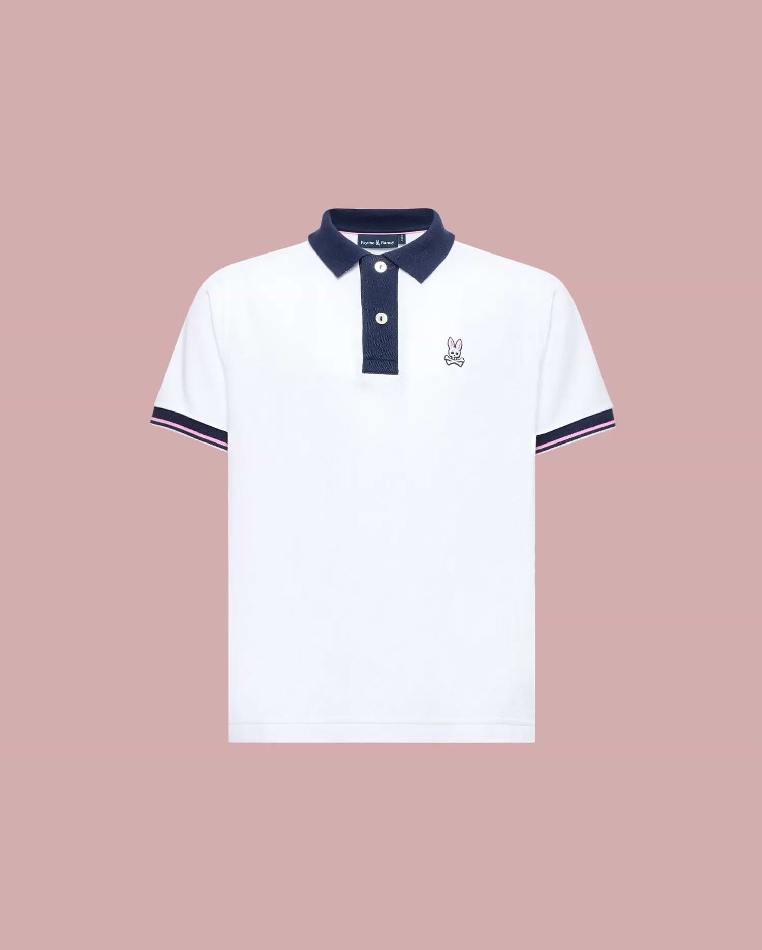 The Psycho Bunny KIDS ARCHIVE CLASSIC BUNNY PIQUE POLO (KT0100010) is a white, short-sleeve Pima cotton shirt with a navy collar and trim, three dark buttons, and an embroidered Bunny logo on the left chest, shown on a pale pink background.