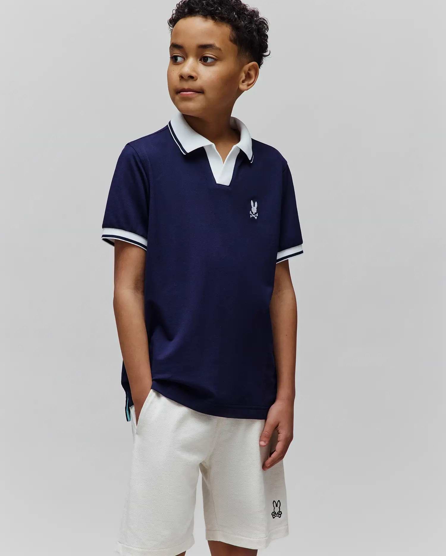 Kids Christiano Pique Polo, classic fit navy pique with white collar and striped cuffs, featuring a small embroidered Psycho Bunny skull logo on the left chest.