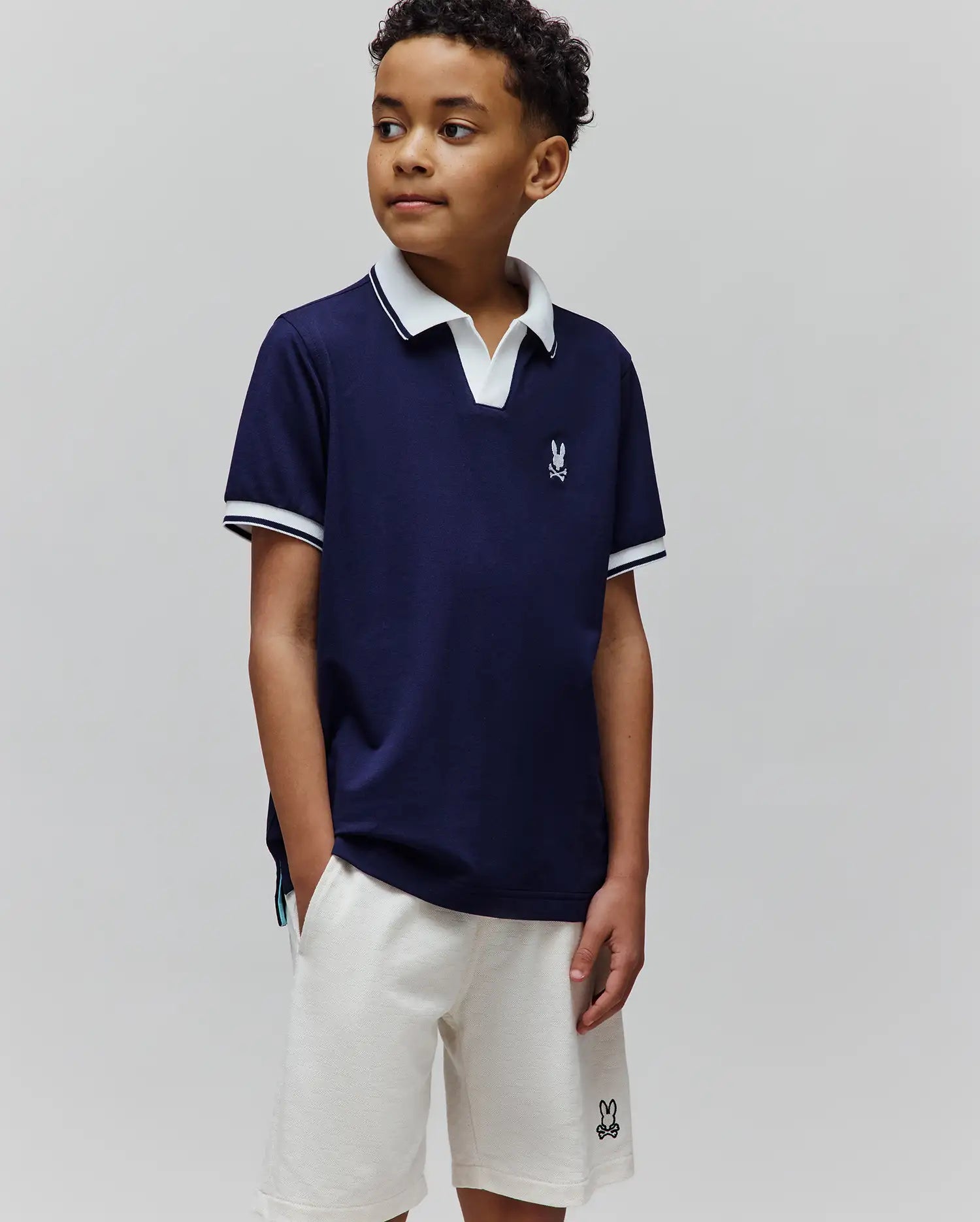 Kids Christiano Pique Polo, classic fit navy pique with white collar and striped cuffs, featuring a small embroidered Psycho Bunny skull logo on the left chest.