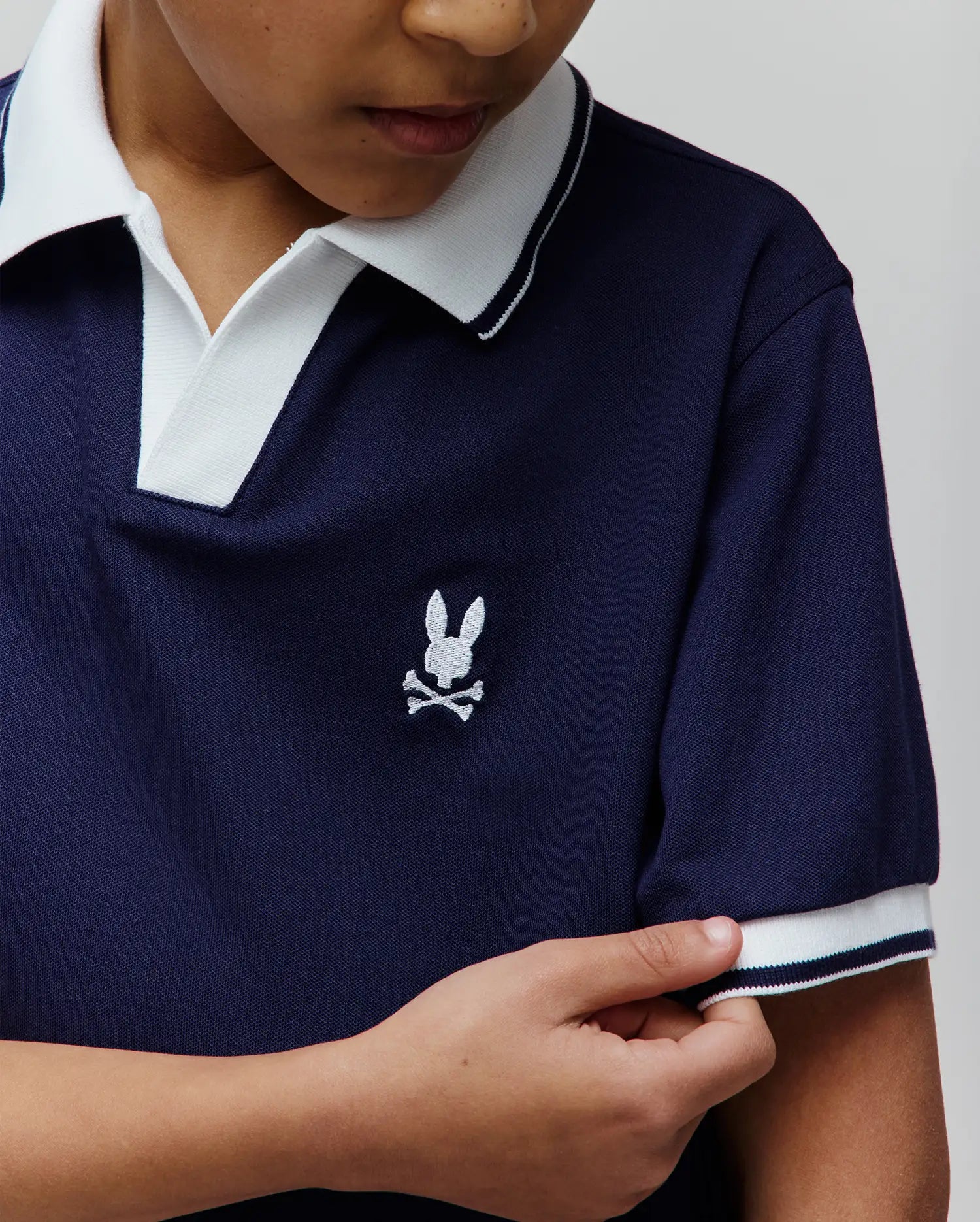 Kids Christiano Pique Polo in navy, featuring a classic fit, pique fabric, white collar with navy stripe, white cuffs with navy stripe, and a small embroidered white Psycho Bunny skull logo on the left chest.