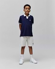 Kids Christiano Pique Polo in navy, classic fit, with white collar, striped cuffs, and embroidered Psycho Bunny skull logo on chest. Cream French terry shorts feature an embroidered bunny logo.