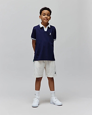 Kids Christiano Pique Polo in navy, classic fit, with white collar, striped cuffs, and embroidered Psycho Bunny skull logo on chest. Cream French terry shorts feature an embroidered bunny logo.