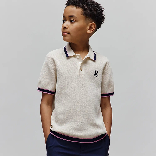 Kids Dax Knit Polo, cream waffle knit with navy and pink striped tipping on collar, cuffs, and hem, featuring a small embroidered black Psycho Bunny skull logo on the left chest.