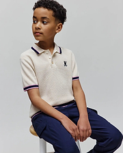 Kids Dax Knit Polo in cream waffle knit with navy and pink striped collar and cuffs, featuring a small embroidered Psycho Bunny skull logo on the left chest.