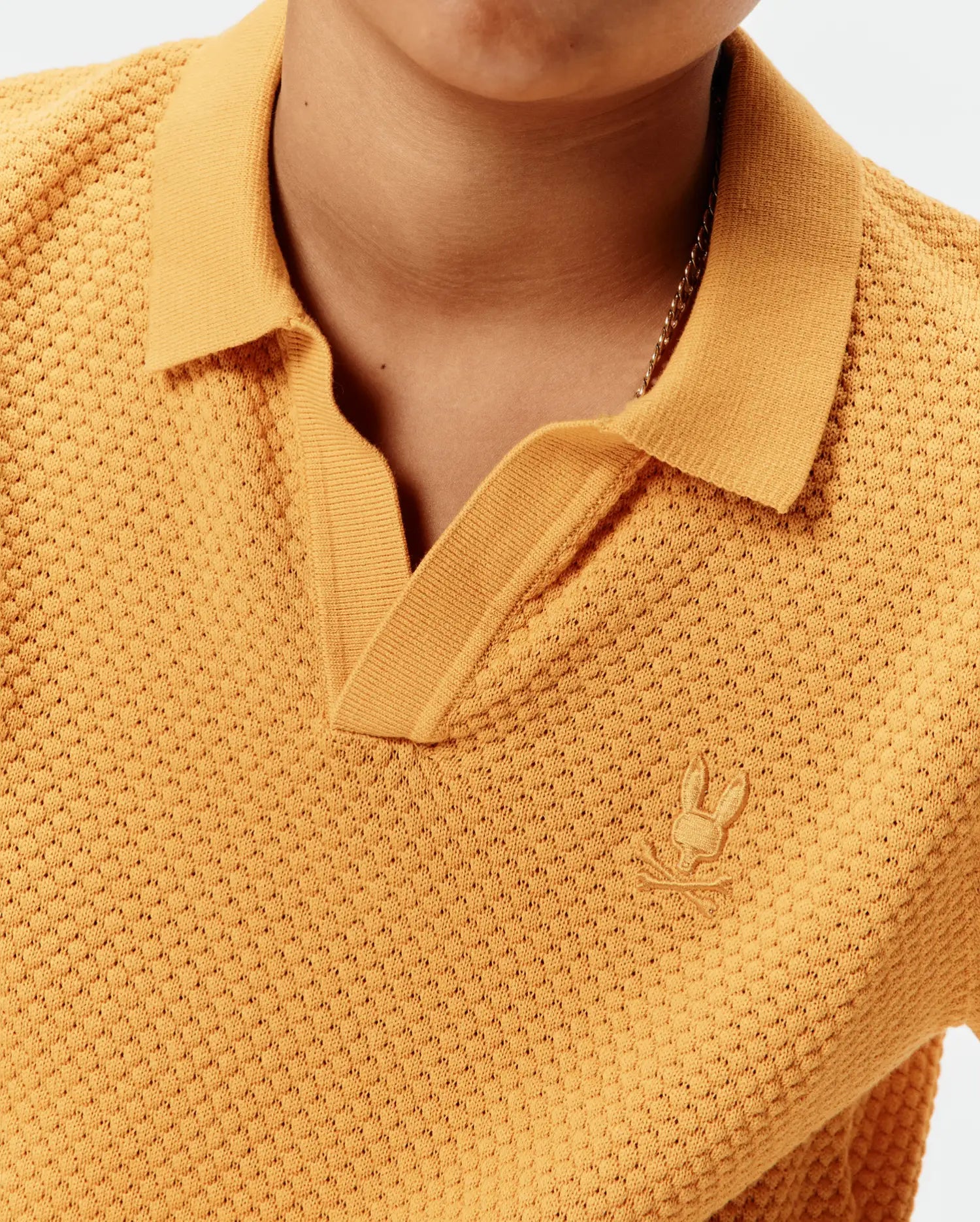Kids Devon Knit Polo in mustard yellow, featuring a textured knit fabric, open collar, and small embroidered Psycho Bunny skull logo on the left chest.