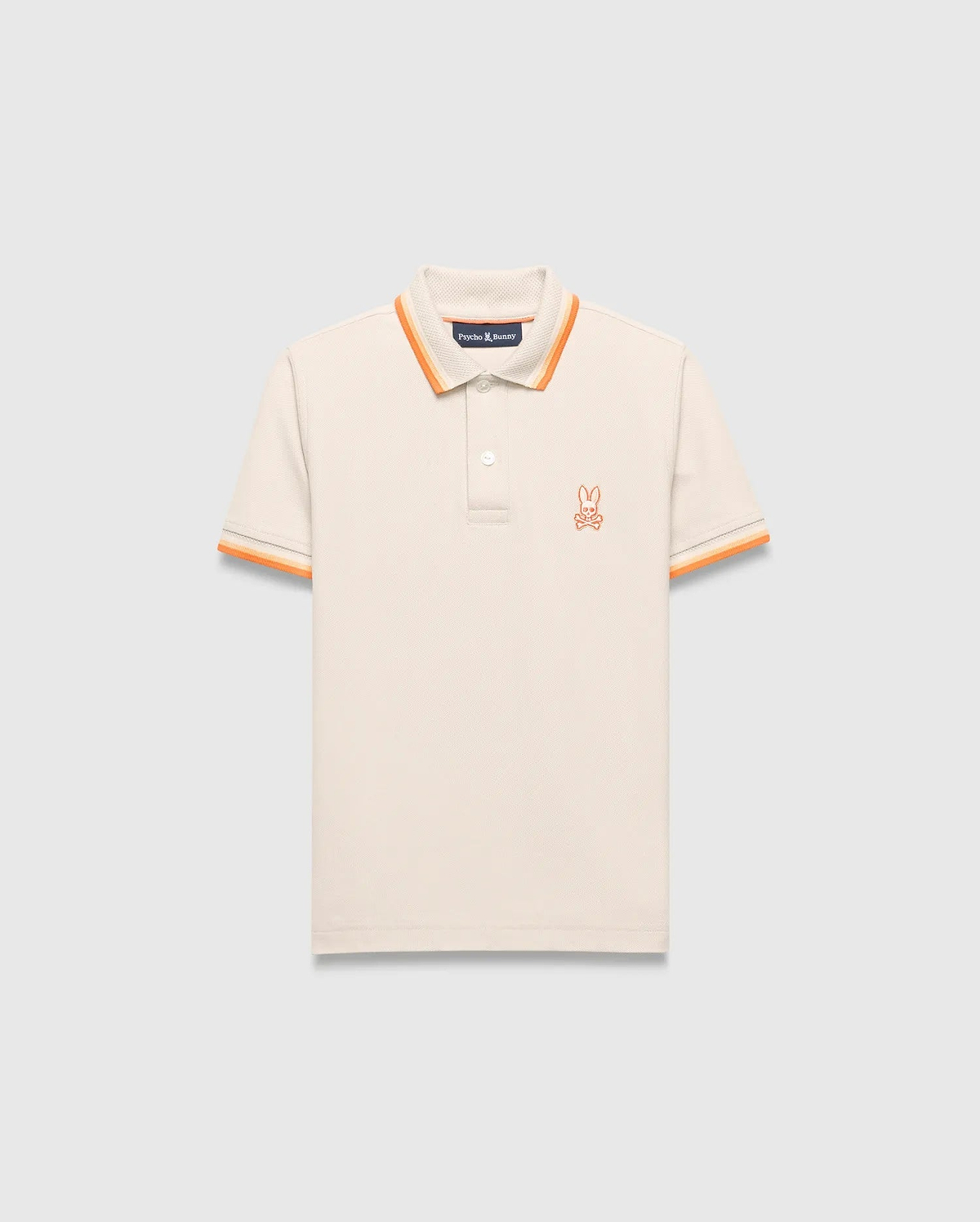 Kids Holden Pique Polo, cream classic fit pique polo with orange striped collar and cuffs, featuring a small embroidered orange Psycho Bunny skull logo on the left chest.