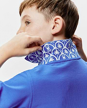 Kids Brad Pique Polo in vibrant royal blue, featuring a classic pique texture and a distinctive inner collar with a white repeating pattern of Psycho Bunny skull logos and palm trees.