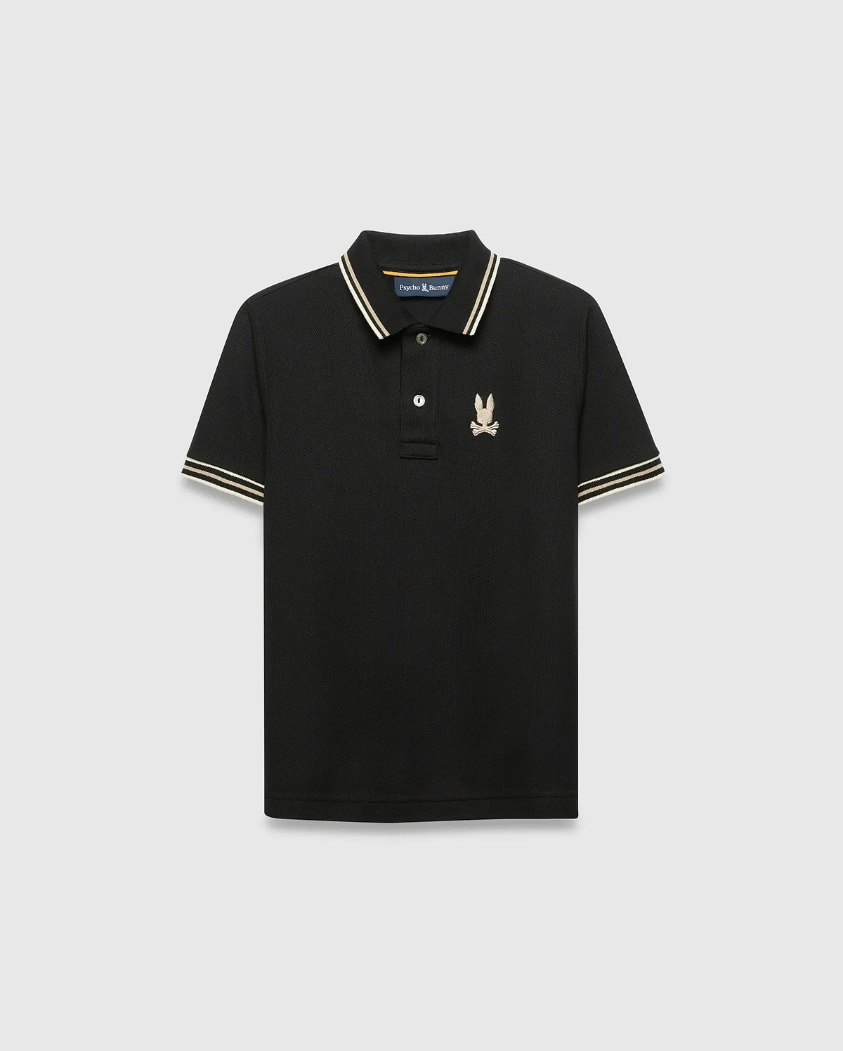 Kids Brad Pique Polo, black classic fit pique knit with gold-tan and white striped collar and cuffs, featuring a small embroidered gold Psycho Bunny skull logo on the left chest.