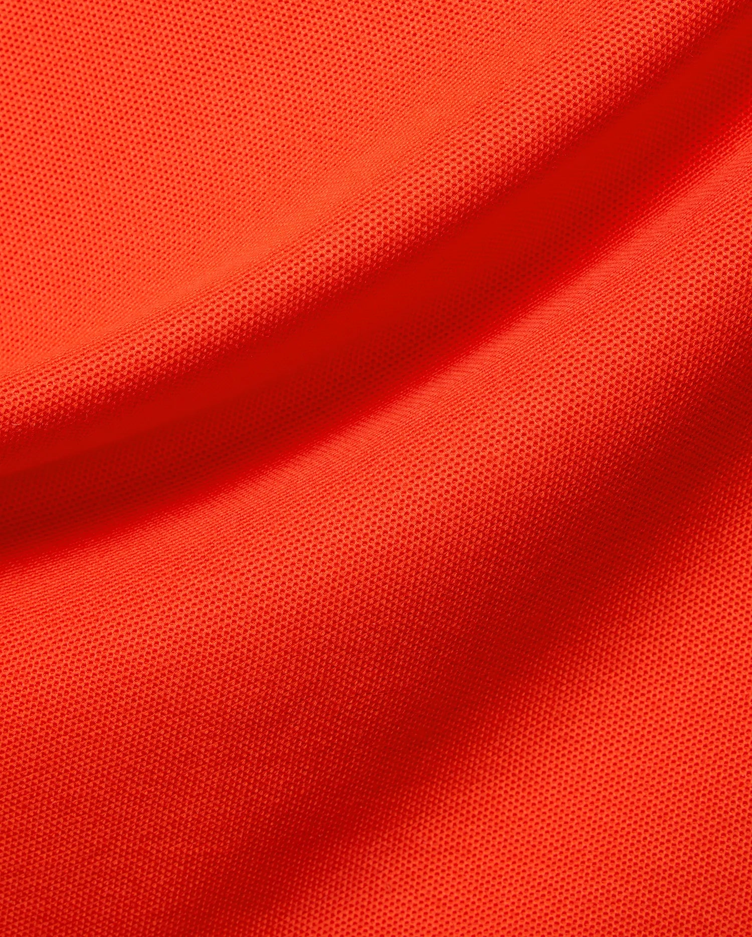 Kids Stan Pique Polo, a premium Psycho Bunny garment in a bold, vibrant orange hue. Close-up reveals the classic textured pique knit fabric with elegant, soft folds, emphasizing quality. (4)
