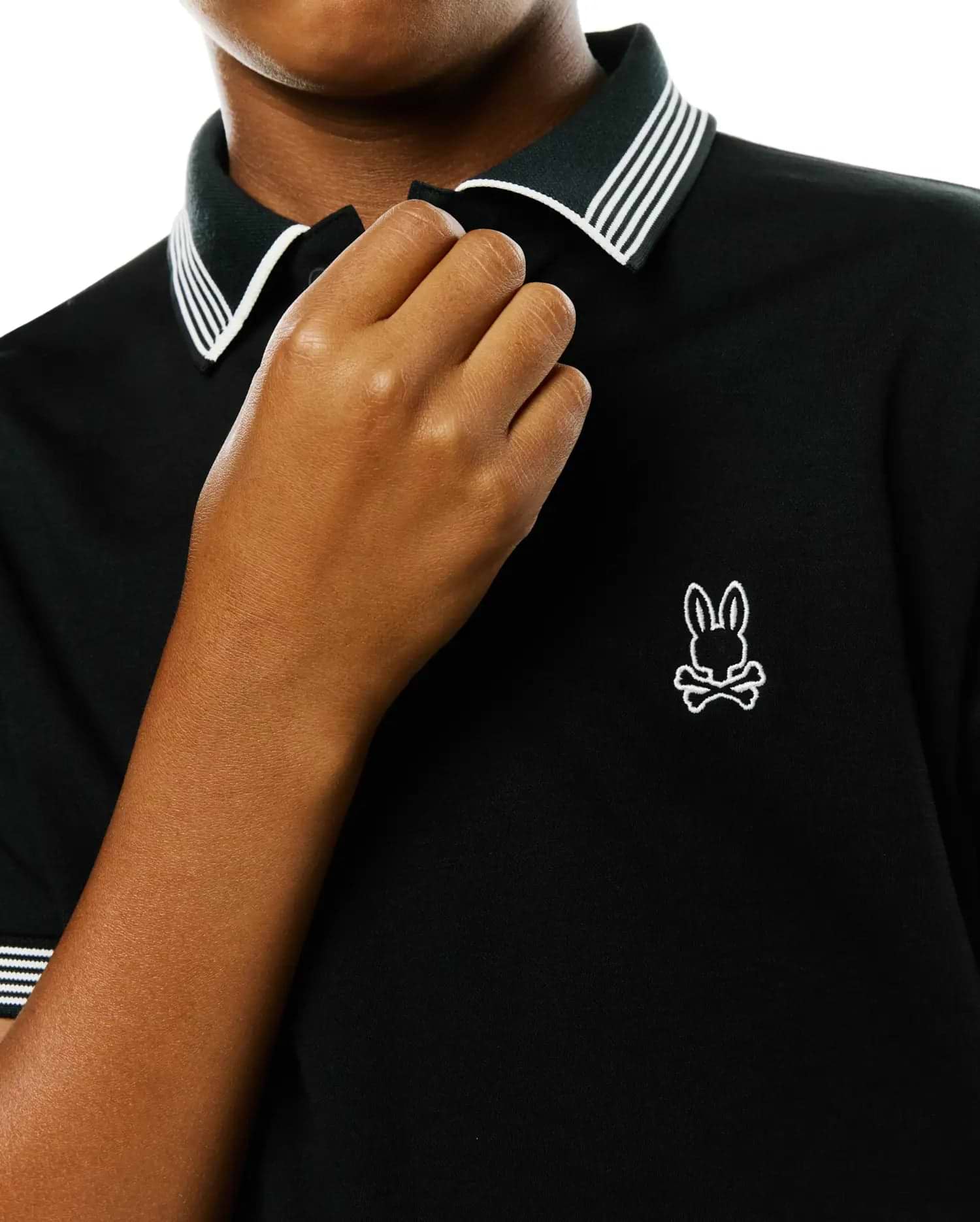 Kids Timmy Pique Polo, a black classic fit pique polo shirt with a ribbed collar and cuffs featuring crisp white stripes, accented by a small, embroidered white Psycho Bunny skull logo on the left chest. (2)
