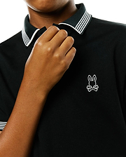 Kids Timmy Pique Polo, a black classic fit pique polo shirt with a ribbed collar and cuffs featuring crisp white stripes, accented by a small, embroidered white Psycho Bunny skull logo on the left chest. (2)