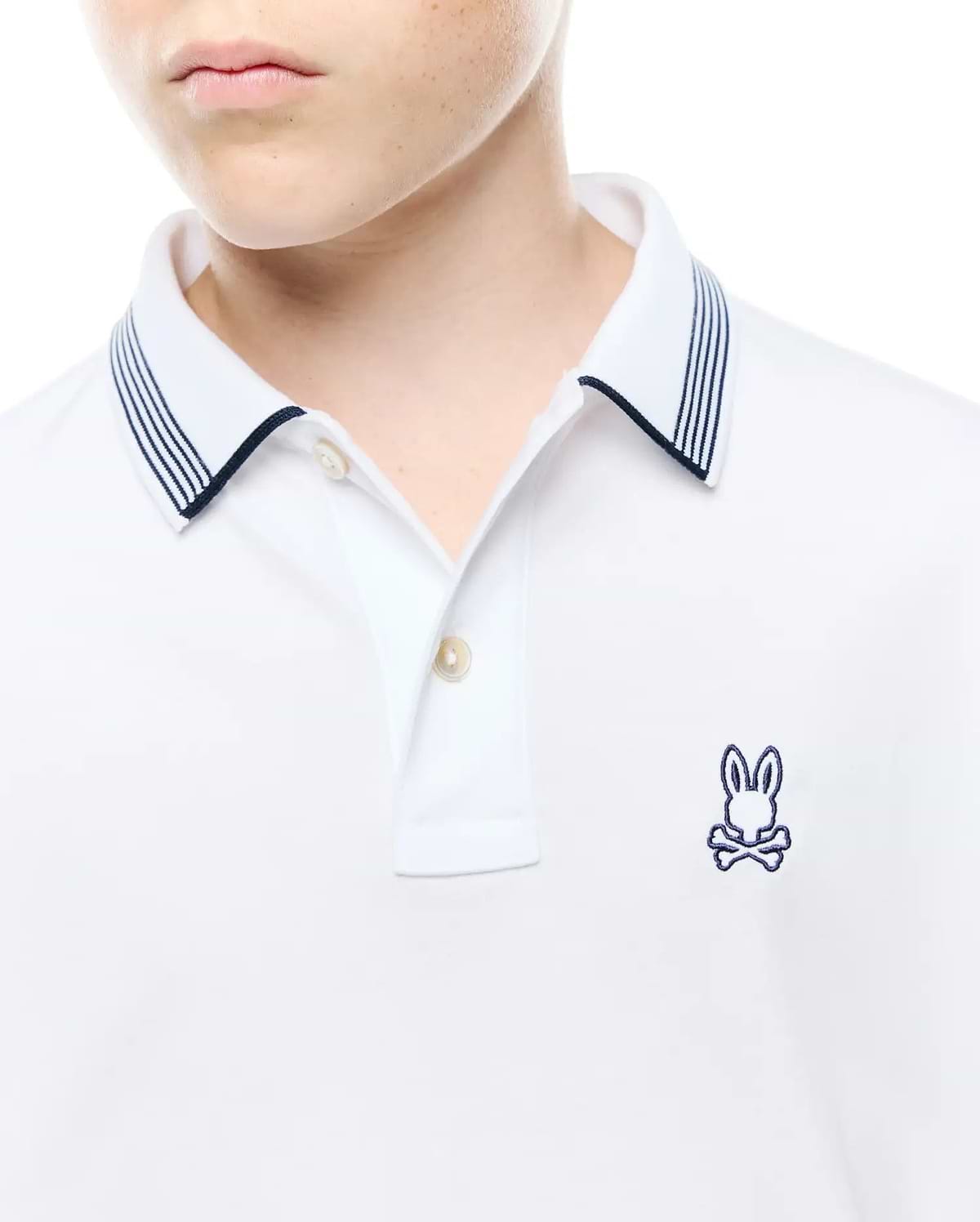 Kids Timmy Pique Polo, a classic white pique polo featuring a two-button placket, navy blue striped collar, and a small embroidered Psycho Bunny skull logo on the left chest.