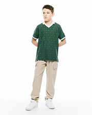 Kids Garry Jacquard Johnny Collar Polo in dark green, featuring an all-over jacquard pattern of small Psycho Bunny skull logos, a white V-neck Johnny collar, and white striped cuffs. Classic fit.