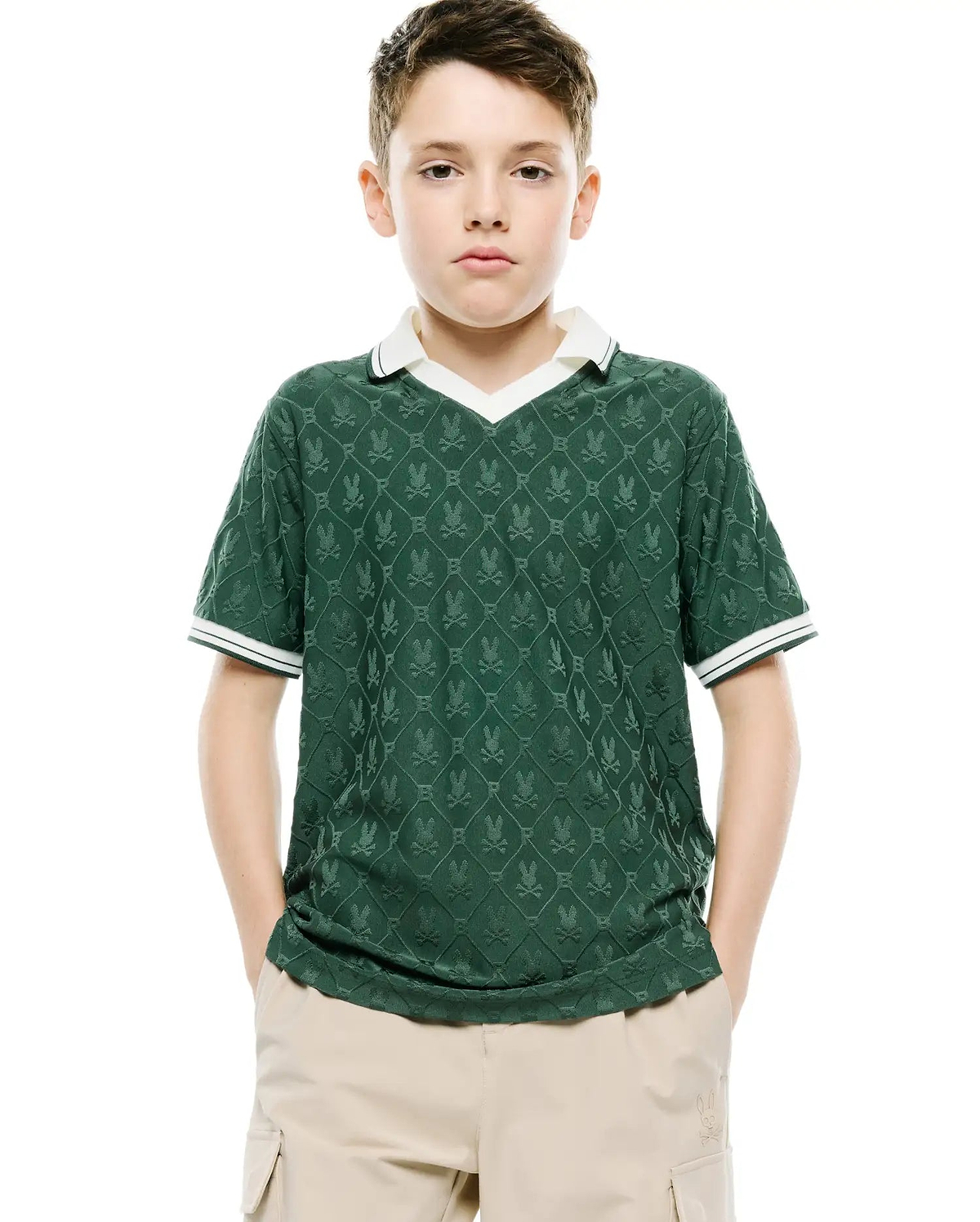 Kids Garry Jacquard Johnny Collar Polo, a classic fit dark green jacquard knit polo with an all-over Psycho Bunny skull logo pattern, white V-neck collar, and striped cuffs.