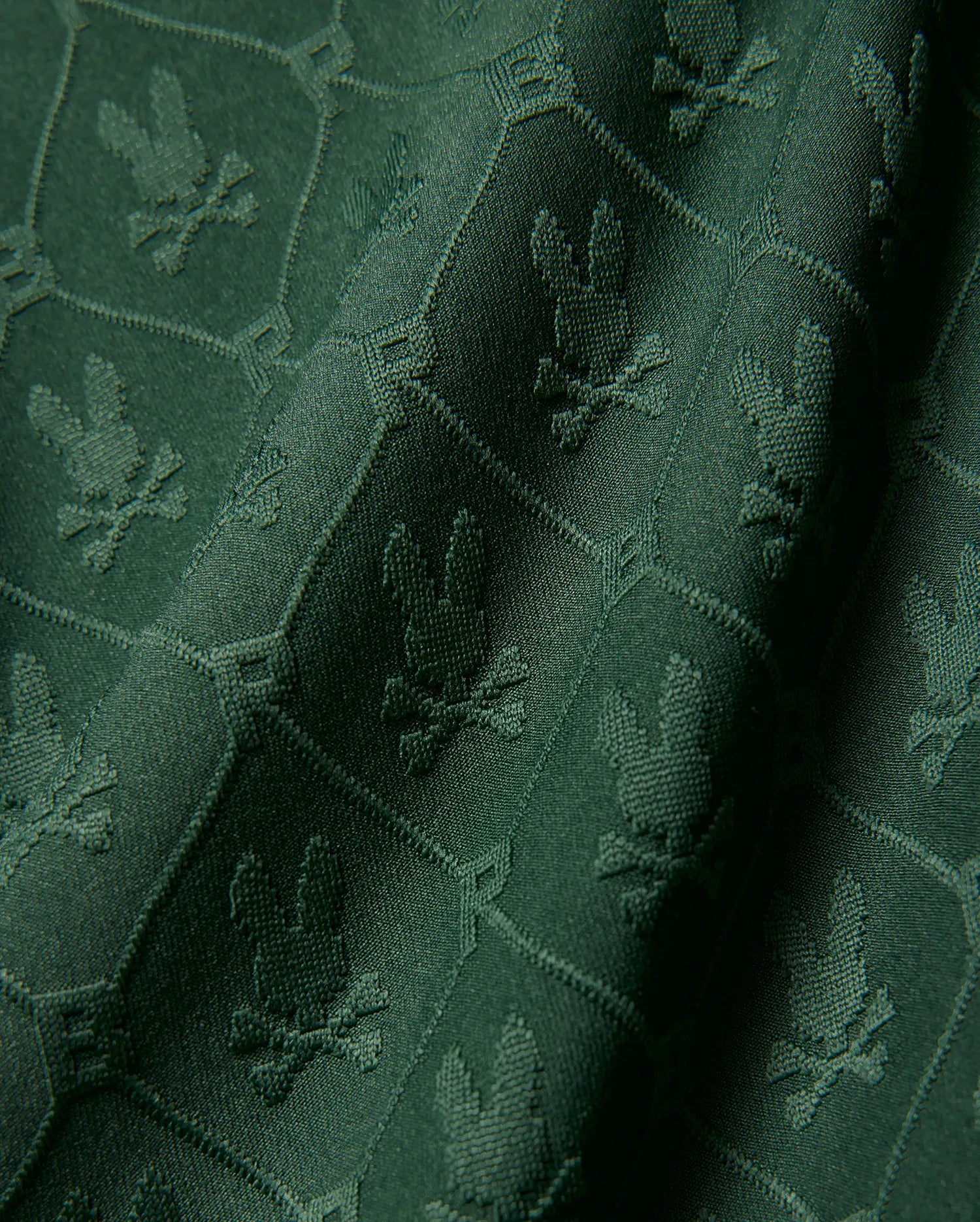 Kids Garry Jacquard Johnny Collar Polo in deep green, featuring an all-over tonal jacquard knit pattern of the iconic Psycho Bunny skull logo within a subtle geometric grid.