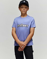 A young boy in a black cap and Psycho Bunny KIDS WADE GRAPHIC TEE (KT0200055) stands against a light gray background, looking at the camera with hands clasped. The lavender tee features 100% cotton, regular fit, cartoon bunny, and "PSYBNY" text.