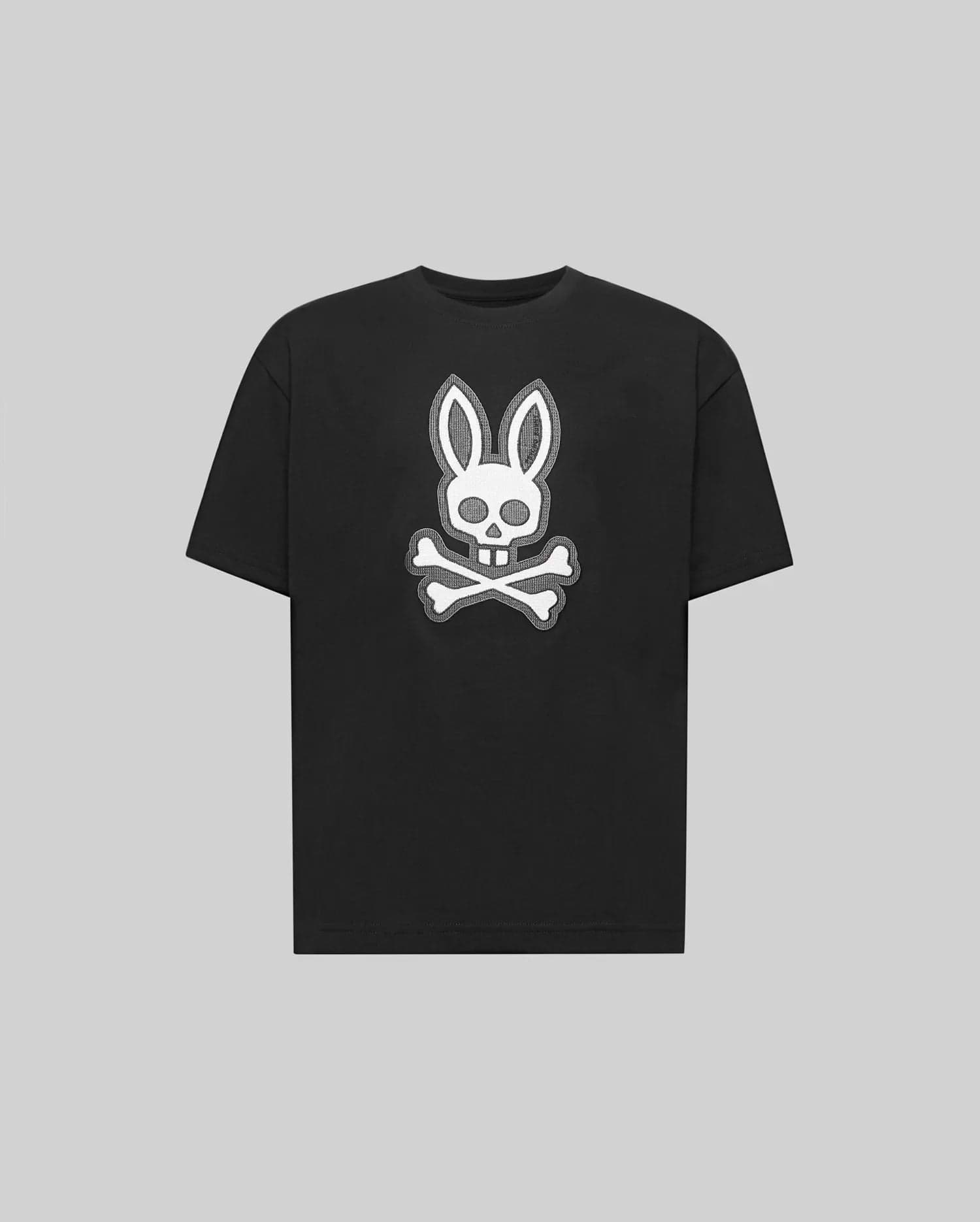 The Psycho Bunny KIDS RYDER OVERSIZED FIT TEE (KT0200056) is a black premium tee crafted from soft Pima cotton, featuring a white embroidered Bunny skull with bunny ears above crossed bones against a gray background.