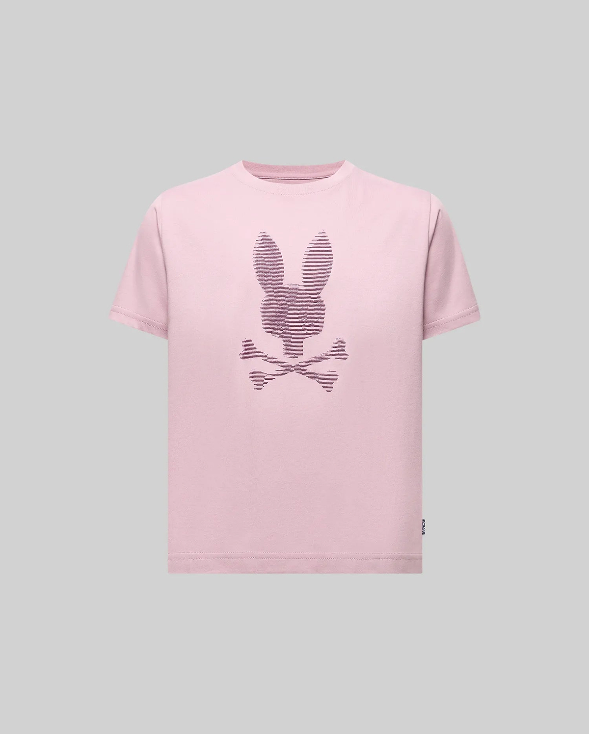 The Psycho Bunny KIDS GRANT BUNNY GRAPHIC TEE (KT0200061) features a light pink Pima cotton shirt with a bunny-head skull and crossbones design in thin dark lines, shown on a plain gray background.