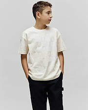 Cream Kids Dustin Oversized Tee with an all-over embossed checkerboard pattern of small Psycho Bunny skull logos and textured squares.