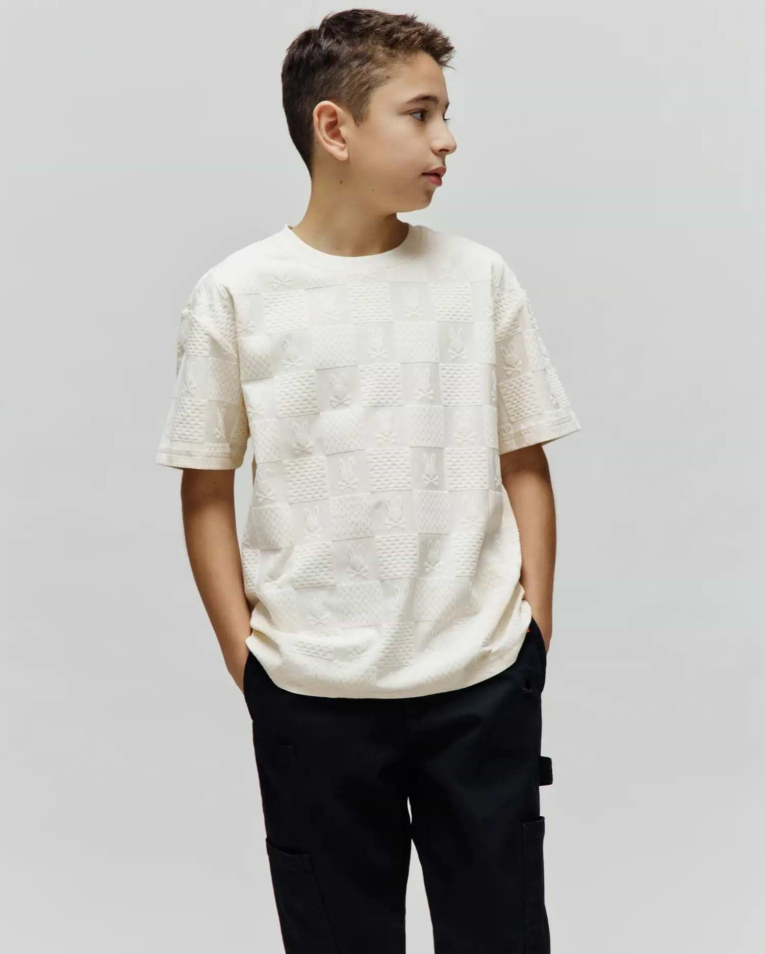Cream Kids Dustin Oversized Tee with an all-over embossed checkerboard pattern of small Psycho Bunny skull logos and textured squares.