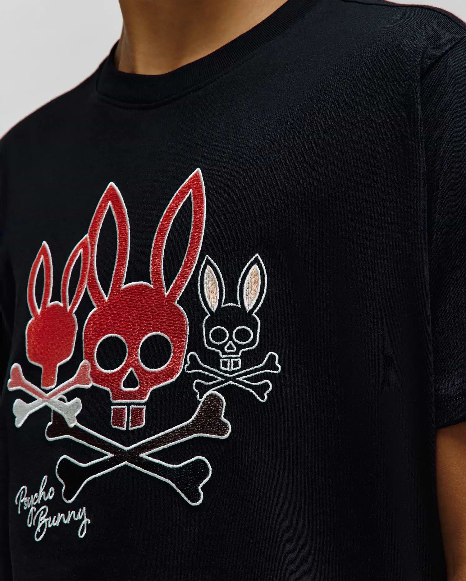 Black Kids Oscar Graphic Tee, classic fit jersey, with a large embroidered chest graphic of three red, white, and brown Psycho Bunny skull and crossbones, plus script branding. (3)