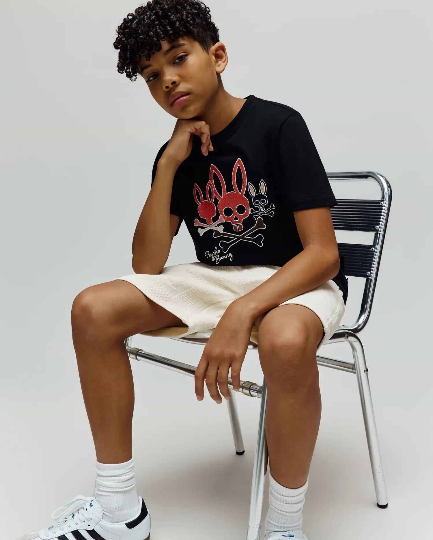 Kids Oscar Graphic Tee, black jersey knit, classic fit. Features a bold central graphic with two red bunny skulls, a white bunny skull, crossed bones, and Psycho Bunny text. (4)