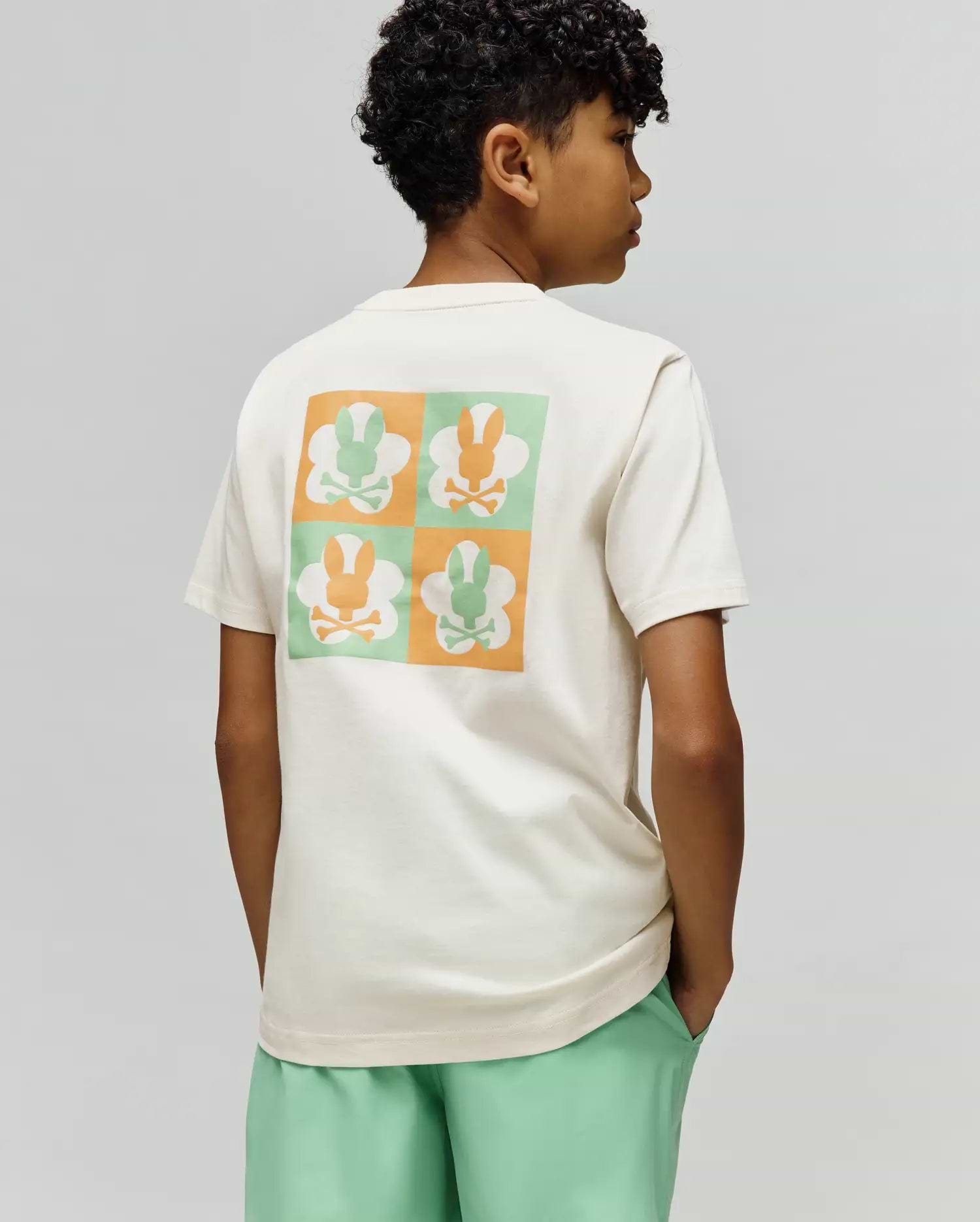 Kids Aiden Back Graphic Tee, a cream classic fit jersey t-shirt with a large back graphic featuring a checkerboard of orange and mint green Psycho Bunny skull logos.