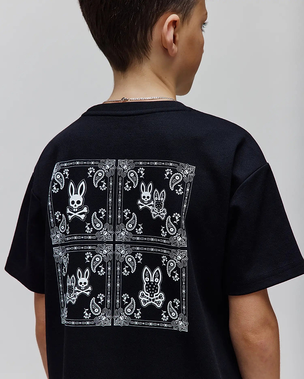 Kids Luke Back Graphic Tee, a black classic fit jersey t-shirt with a large white bandana-style graphic on the back featuring multiple Psycho Bunny skull logos and paisley patterns.