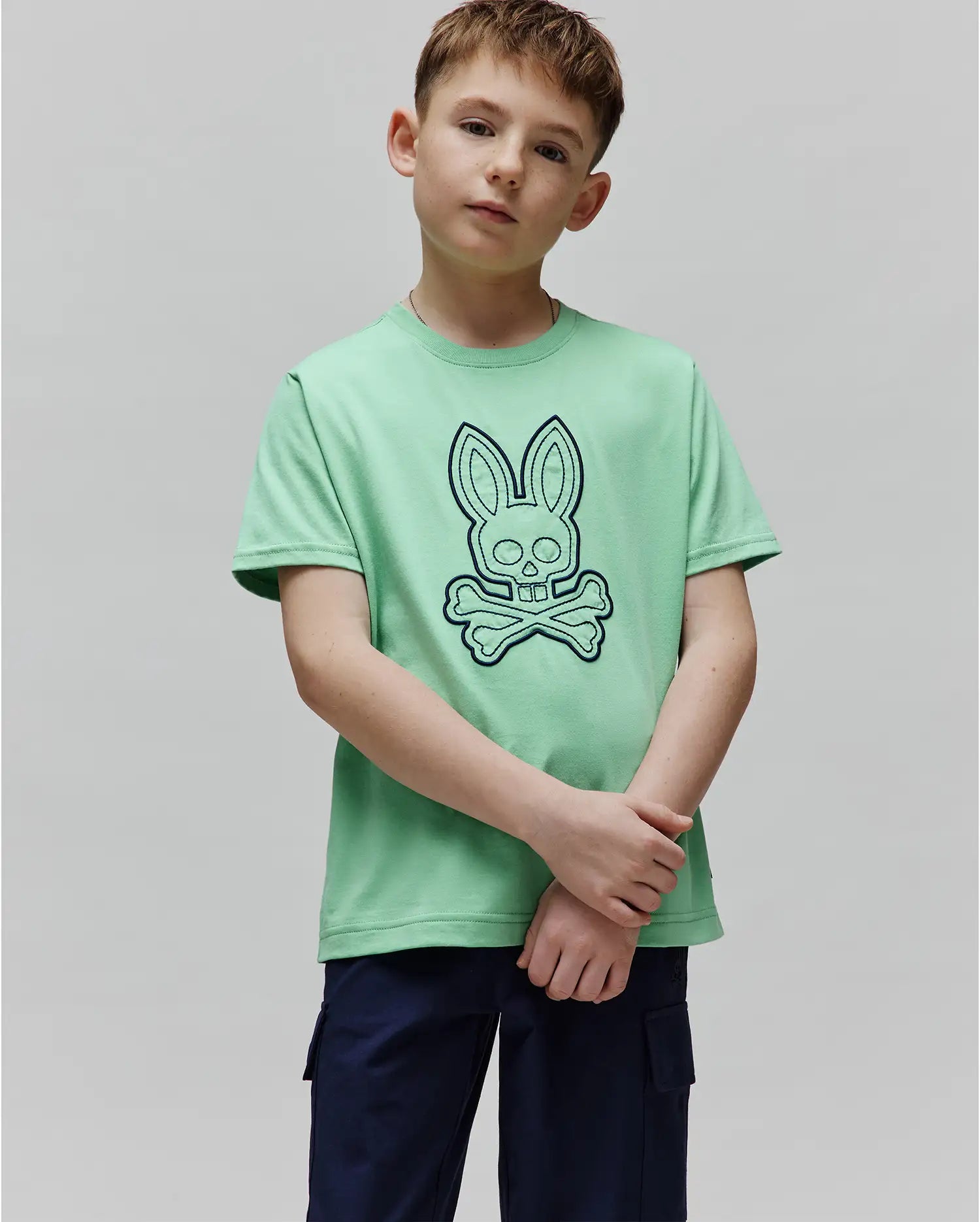 Kids Marcel Graphic Tee, a mint green classic fit jersey t-shirt featuring a large navy outline Psycho Bunny skull logo prominently centered on the chest. (4)