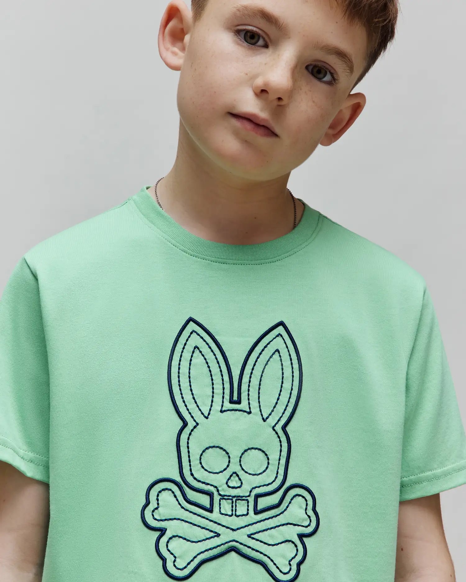 Kids Marcel Graphic Tee in mint green, featuring a large, central dark blue embroidered Psycho Bunny skull and crossbones logo on soft jersey knit fabric with a classic fit. (3)